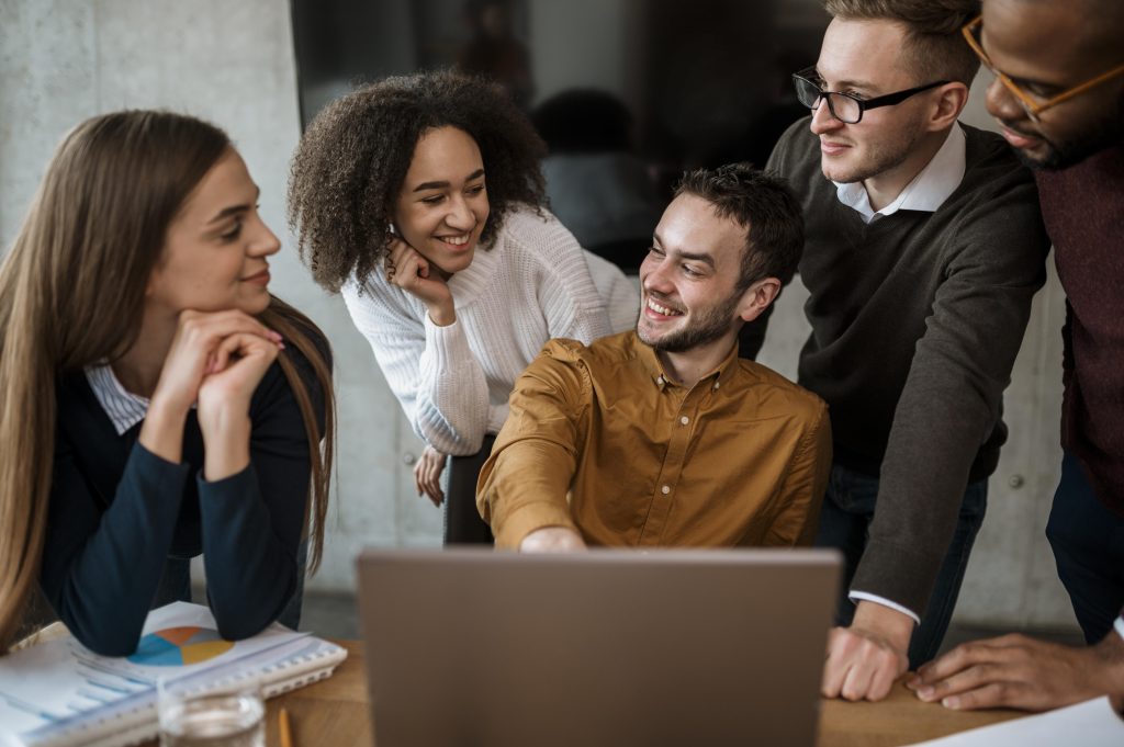 cinco pessoas reunidas em uma sala em frente a um computador, representando o que é gestão de conflitos