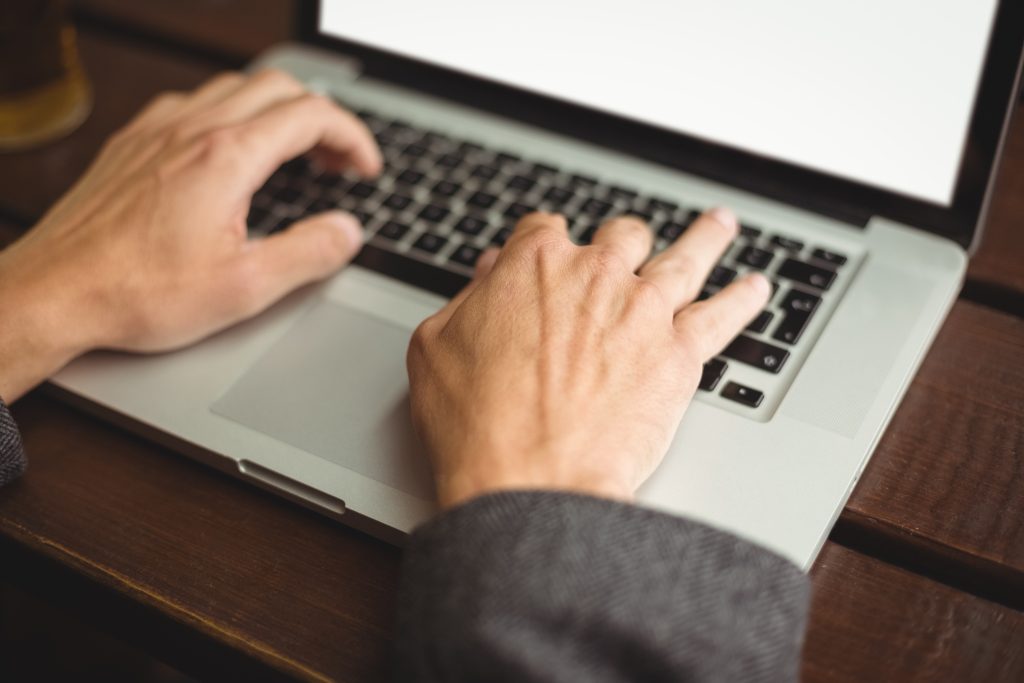 Mão masculina digitando no computador em um escritório. Representando o que é ensino híbrido