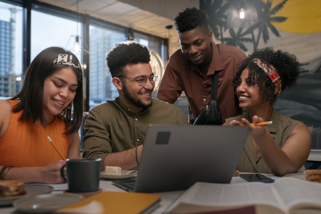 quatro pessoas reunidas em uma sala em frente a um computador, representando o que é capacitação de pessoas