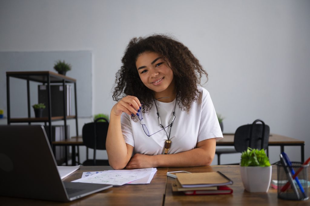 na imagem tem uma mulher em um escritório com papeis sobre a mesa. Representando o que é desenvolvimento pessoal e profissional